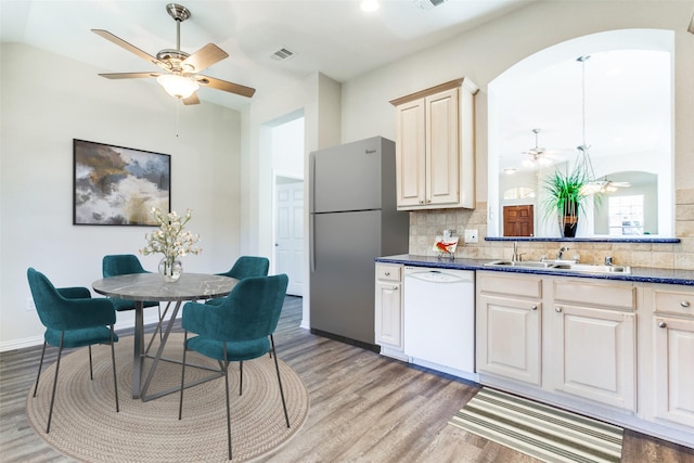 kitchen featuring visible vents, a sink, freestanding refrigerator, white dishwasher, and light wood finished floors