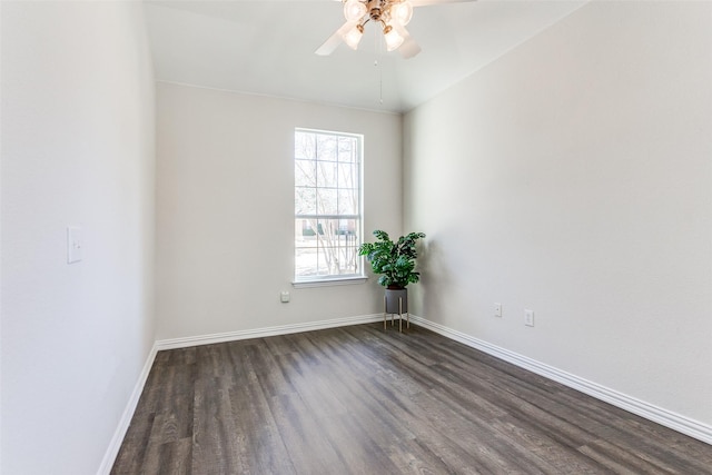 unfurnished room featuring baseboards, dark wood finished floors, and a ceiling fan