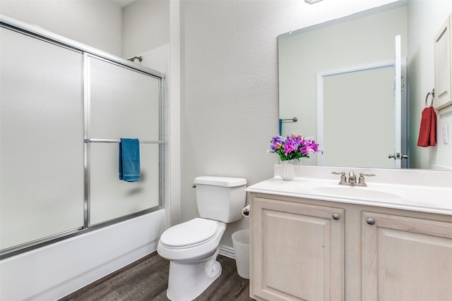 full bathroom featuring combined bath / shower with glass door, toilet, vanity, and wood finished floors