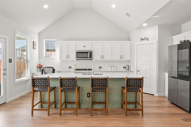 kitchen with stainless steel appliances, a sink, visible vents, light countertops, and light wood finished floors