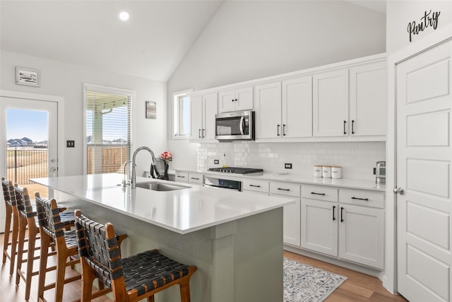 kitchen with lofted ceiling, stainless steel microwave, a sink, a kitchen bar, and backsplash