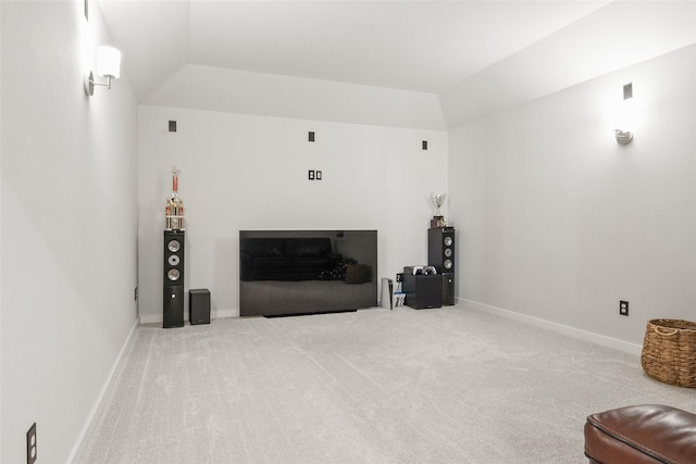 carpeted living room featuring lofted ceiling, a fireplace, and baseboards