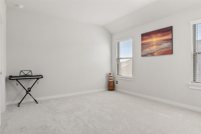 carpeted spare room featuring vaulted ceiling and baseboards