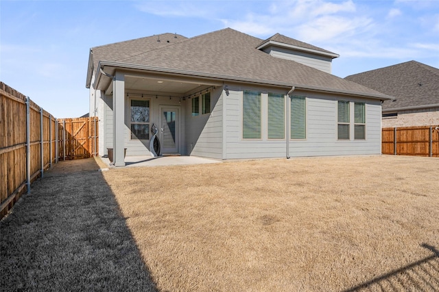 rear view of property with a yard, a shingled roof, a patio area, and a fenced backyard