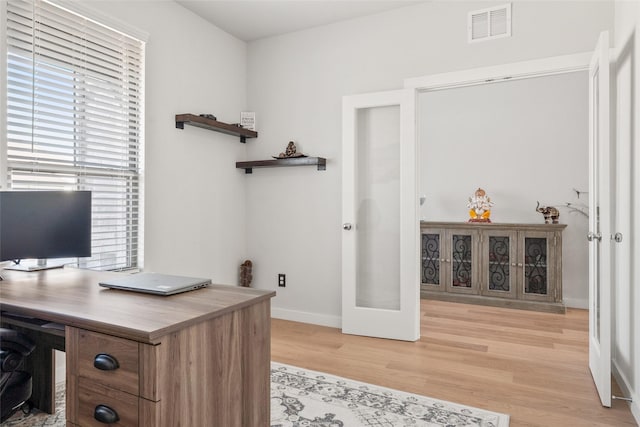 office with light wood-style floors, french doors, visible vents, and baseboards