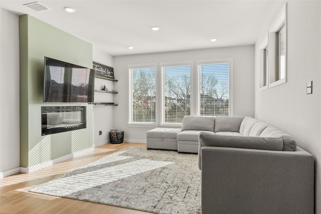 living area featuring baseboards, visible vents, wood finished floors, and recessed lighting