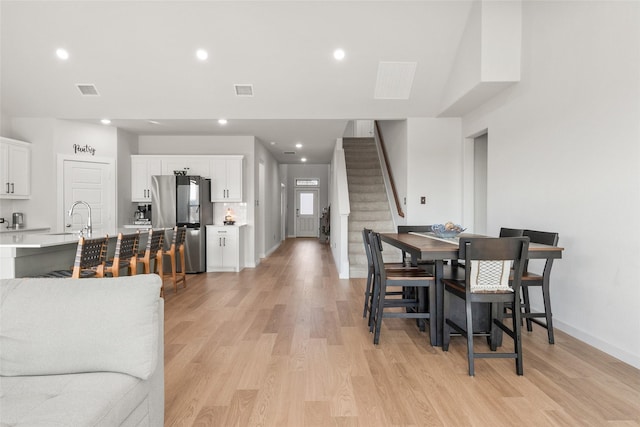 dining area featuring light wood finished floors, recessed lighting, visible vents, baseboards, and stairs