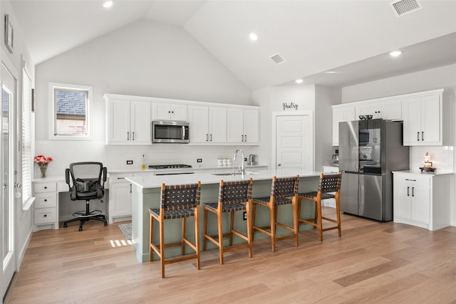 kitchen featuring stainless steel appliances, visible vents, a sink, and light wood-style flooring