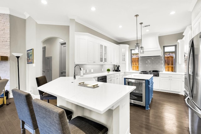 kitchen featuring arched walkways, wine cooler, a peninsula, visible vents, and custom range hood