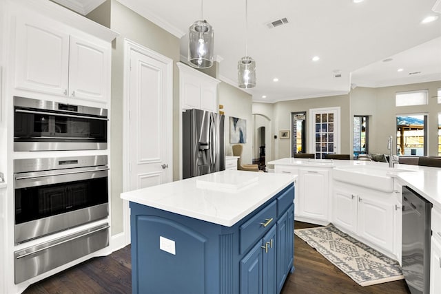 kitchen with arched walkways, a warming drawer, blue cabinetry, stainless steel appliances, and a sink