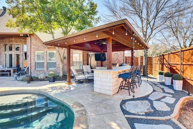 view of patio featuring a fenced backyard, outdoor dry bar, and ceiling fan