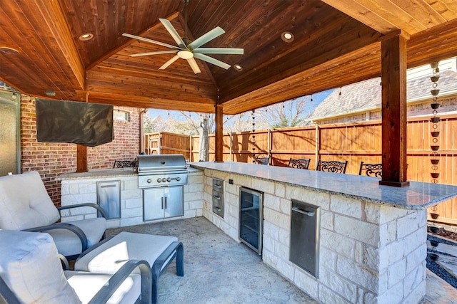 view of patio / terrace with beverage cooler, area for grilling, ceiling fan, fence, and a gazebo