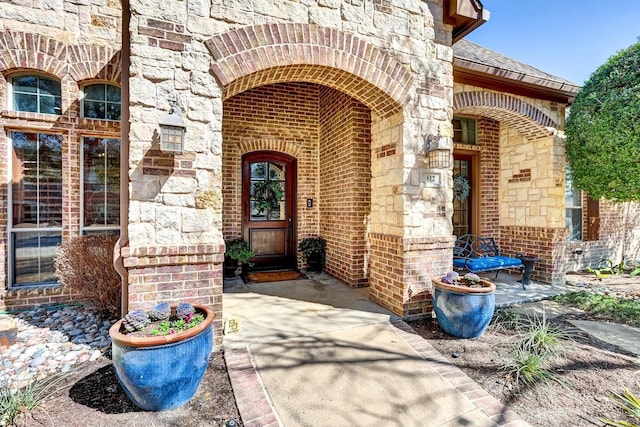 property entrance with stone siding, brick siding, and roof with shingles