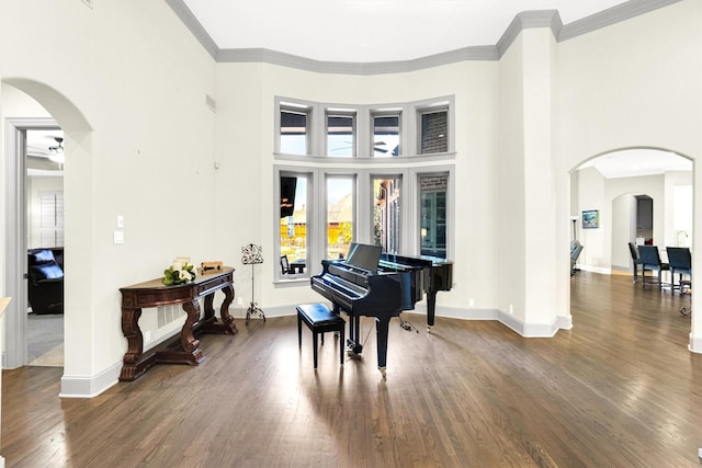 living area with arched walkways, dark wood-type flooring, ornamental molding, and baseboards