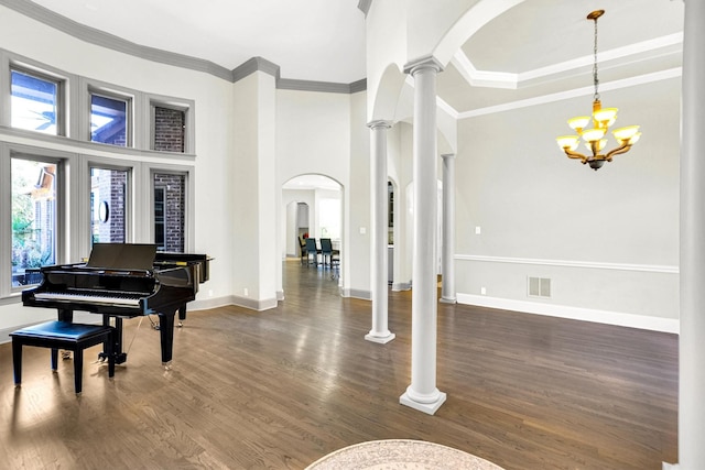 entrance foyer featuring arched walkways, wood finished floors, visible vents, ornate columns, and crown molding