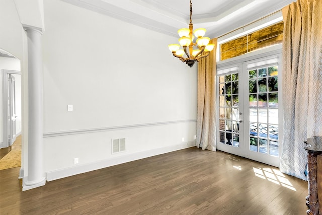 unfurnished dining area with wood finished floors, french doors, ornate columns, a tray ceiling, and crown molding