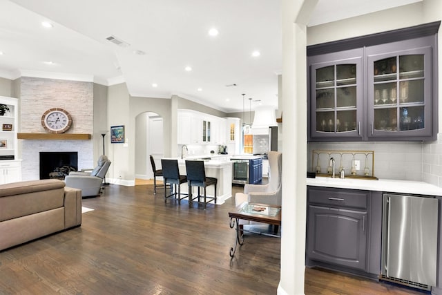 interior space with dark wood-style floors, a large fireplace, visible vents, and crown molding