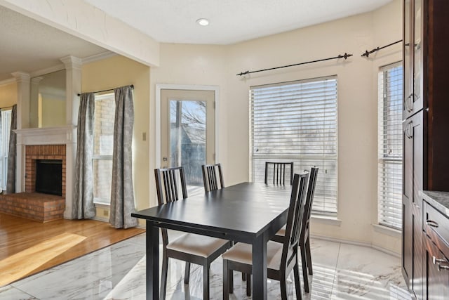 dining space featuring marble finish floor, a brick fireplace, and baseboards