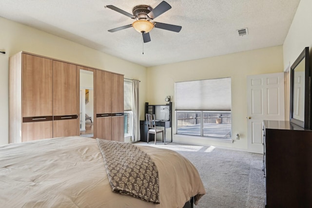 bedroom with visible vents, light colored carpet, a ceiling fan, and a textured ceiling