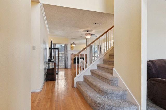 stairway with visible vents, baseboards, a textured ceiling, and hardwood / wood-style floors