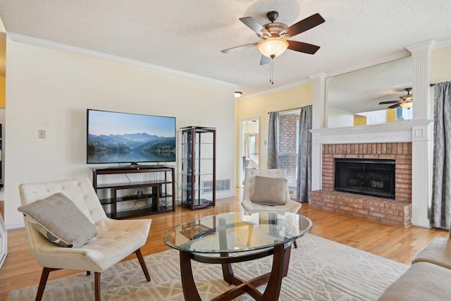 living area with visible vents, ornamental molding, a brick fireplace, and wood finished floors