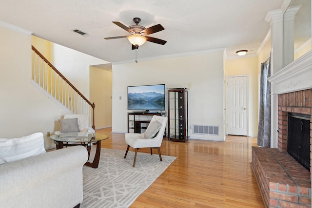 living area featuring visible vents, a fireplace, light wood-type flooring, and ornamental molding