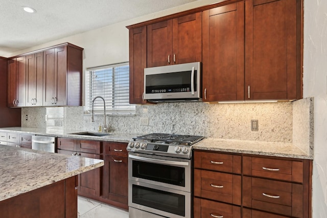 kitchen featuring light stone counters, decorative backsplash, marble finish floor, stainless steel appliances, and a sink