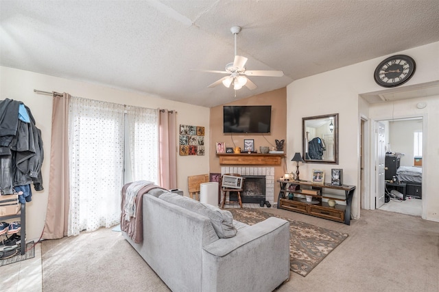 carpeted living room featuring ceiling fan, a textured ceiling, a brick fireplace, attic access, and vaulted ceiling