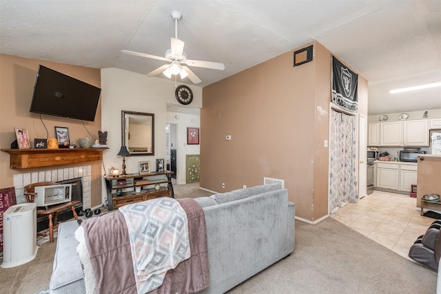 living area with lofted ceiling, ceiling fan, a textured ceiling, a brick fireplace, and light colored carpet