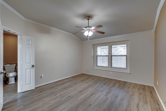 spare room with baseboards, a ceiling fan, ornamental molding, vaulted ceiling, and light wood-type flooring