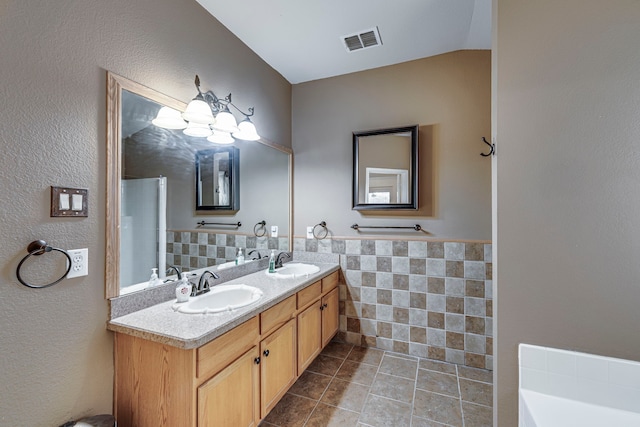 bathroom with tile walls, tile patterned flooring, visible vents, and a sink