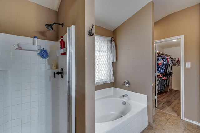 full bathroom with a shower stall, a walk in closet, a bath, and tile patterned floors