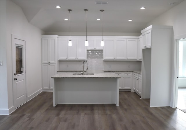 kitchen with light stone counters, dark wood-style flooring, a center island with sink, white cabinets, and a sink