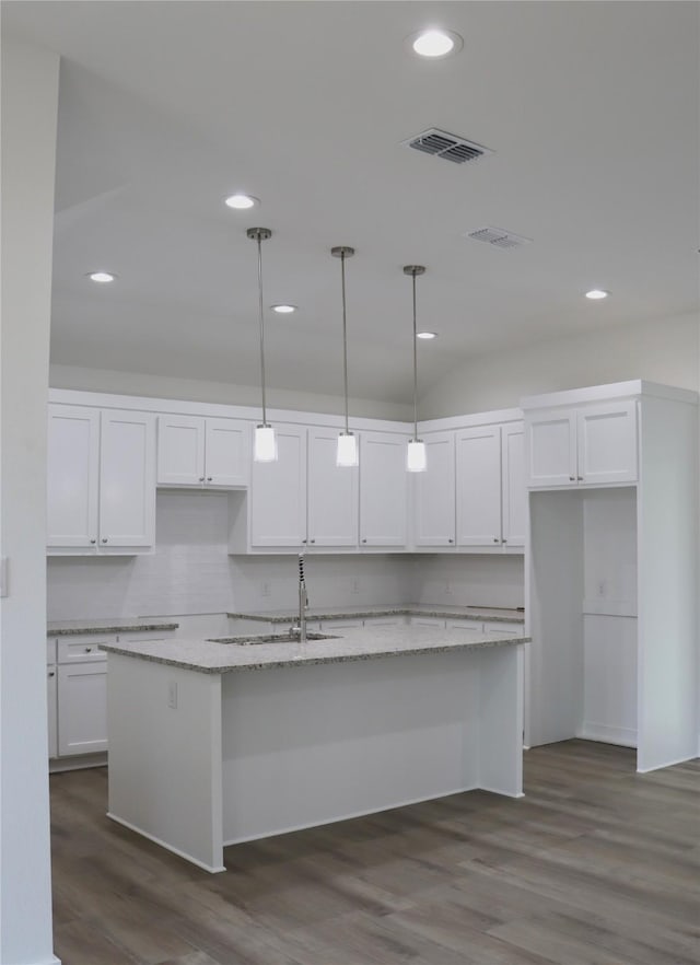 kitchen with a sink, visible vents, white cabinets, dark wood finished floors, and a center island with sink