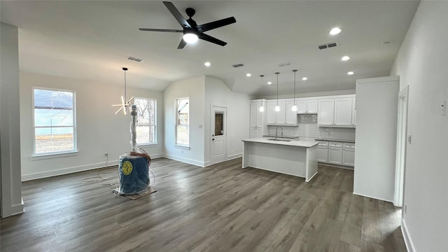 kitchen with a kitchen island with sink, visible vents, open floor plan, and dark wood-type flooring