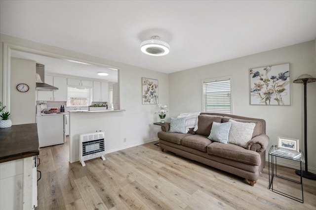 living room featuring heating unit, light wood-style floors, and baseboards