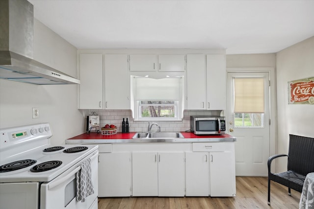 kitchen with white range with electric cooktop, decorative backsplash, stainless steel microwave, wall chimney range hood, and a sink