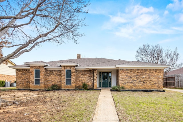 view of front of home with central AC unit, brick siding, fence, a front lawn, and a chimney