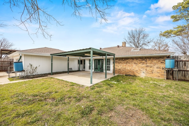 back of house with a lawn, a chimney, fence, a patio area, and brick siding