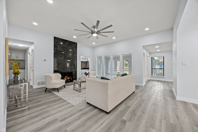 living area with a large fireplace, light wood-style floors, and recessed lighting