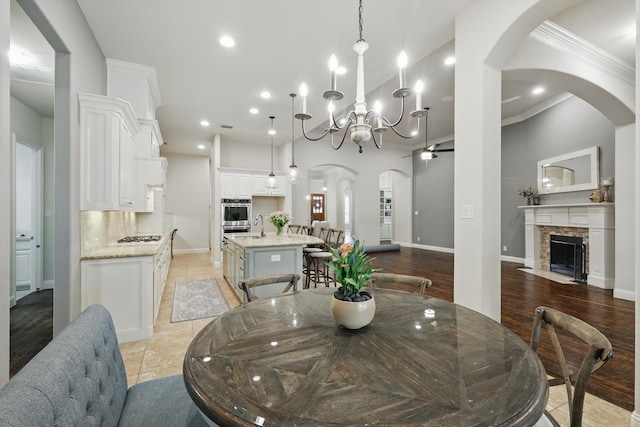 dining area featuring arched walkways, a stone fireplace, recessed lighting, and baseboards