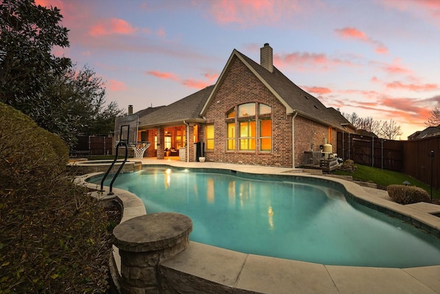 pool at dusk featuring a fenced in pool, a fenced backyard, and a patio area