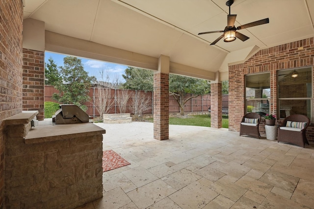 view of patio with ceiling fan, area for grilling, a fenced backyard, and exterior kitchen