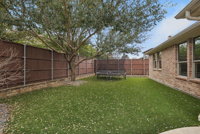 view of yard with a fenced backyard and a trampoline