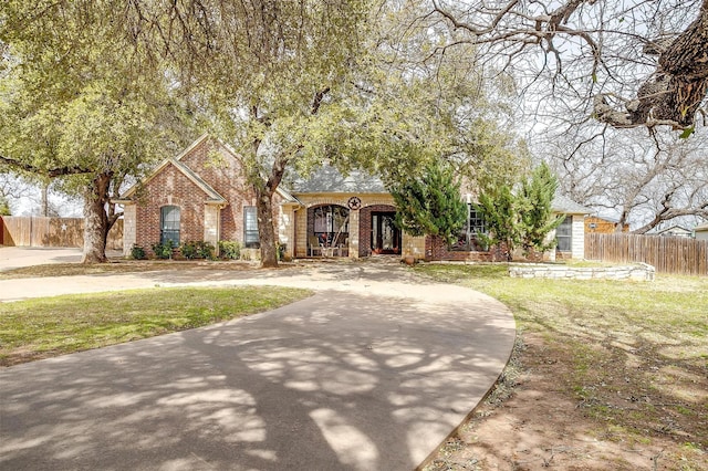 view of front of property with brick siding, a front yard, and fence