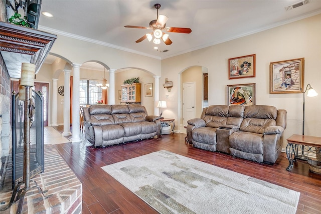 living room with arched walkways, wood finished floors, visible vents, ornate columns, and crown molding