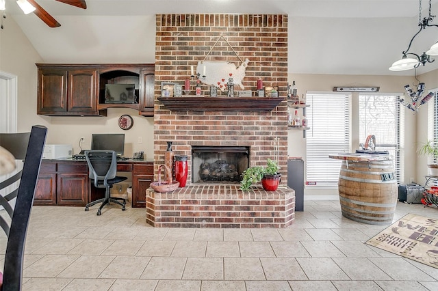 living area featuring lofted ceiling, ceiling fan, light tile patterned floors, a brick fireplace, and built in desk