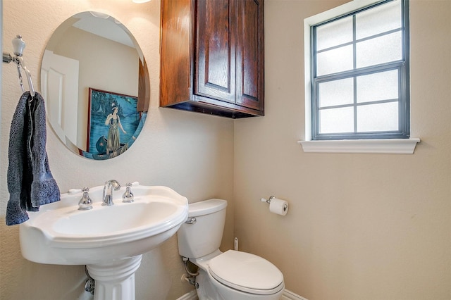 half bath with a sink, toilet, and baseboards