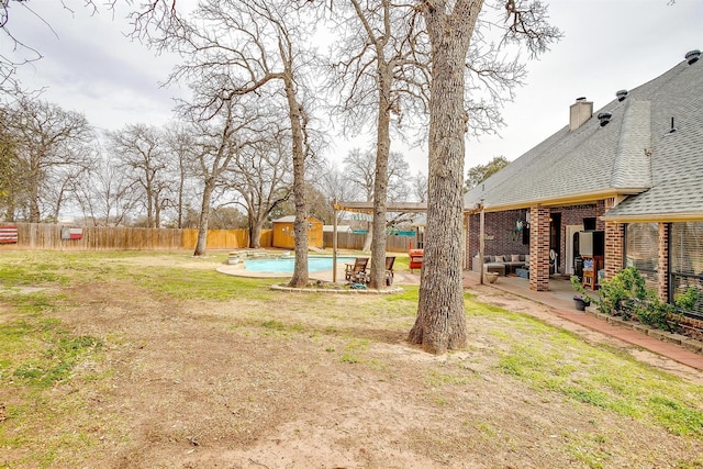 view of yard featuring an outbuilding, a fenced backyard, a fenced in pool, a shed, and a patio area