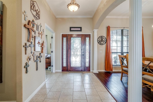 foyer with arched walkways, ornate columns, crown molding, and baseboards